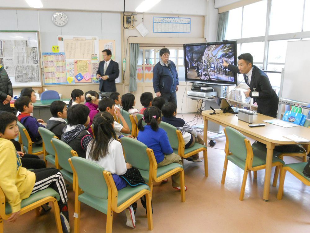 遠隔授業の実施実験の様子。学校で子どもたちがモニターを通じて、博物館の展示室からの授業を受けている