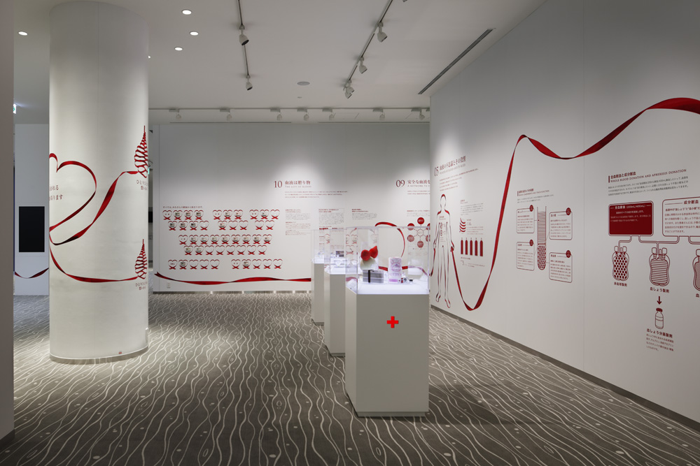 1F展示ホール。空間全体にリボンを配置。血液にまつわるサイエンスの話もわかりやすくデザイン表現