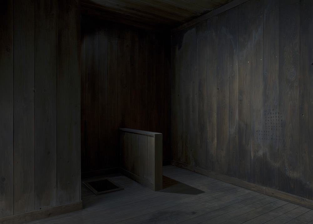 The inside of the cell is so dark that it is impossible to tell if it is day or night. There are traces of counting dates on the wall.