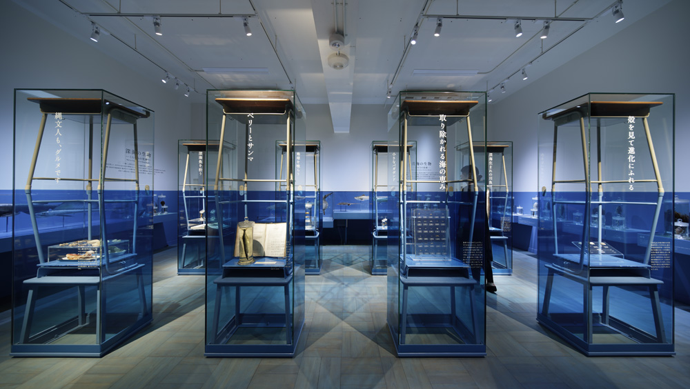 The exhibition room has a sea theme. Cases made of upside-down study desks are arranged in a regular pattern to highlight the lines of the water surface.