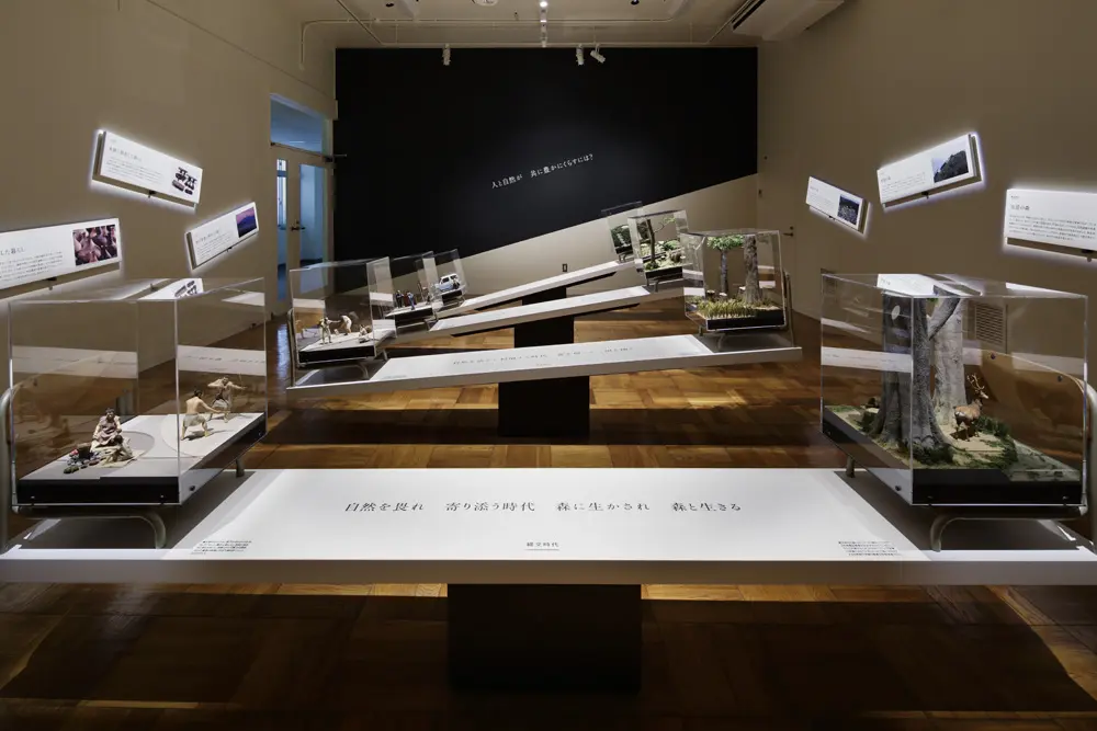 A pair of models representing human life and nature are placed on either end of the balance structure, and the tilt of the structure conveys the changes in the relationship with nature.