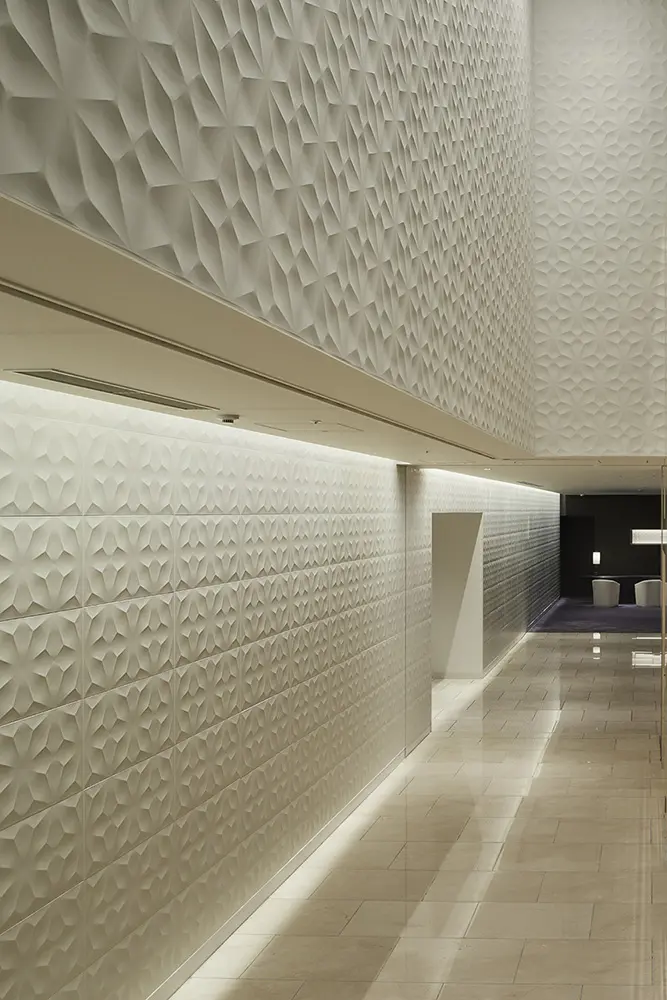 The Hanamichi (walkway) connecting the two lobbies. In keeping with the fact that this was once a sacred place for Kabuki, home to the three Edo theatres, the corridor is designed to resemble a Kabuki hanamichi (walkway) with wall reliefs inspired by the patterns of Kabuki actors.