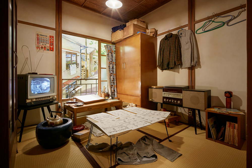 よこたとくおさんの部屋。テレビからは当時のニュース映像やCMが流れ、２階の空間全体に当時の空気感を伝えている
