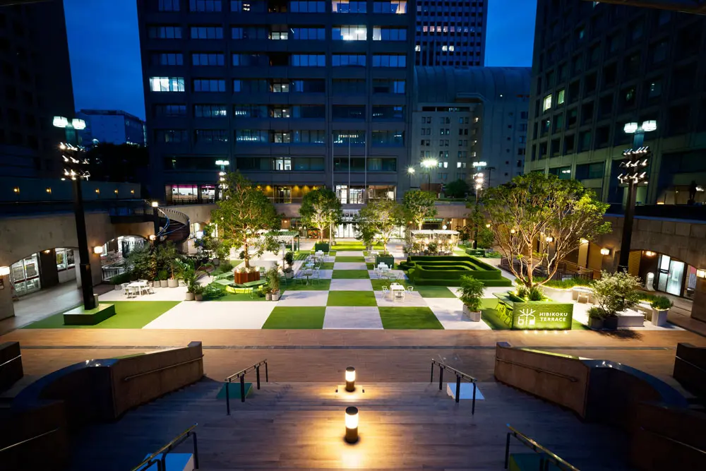 At night, the cafe is lit up with green and white lights. The layout allows both people who want to continue working in the lit space and those who want to enjoy a drink.