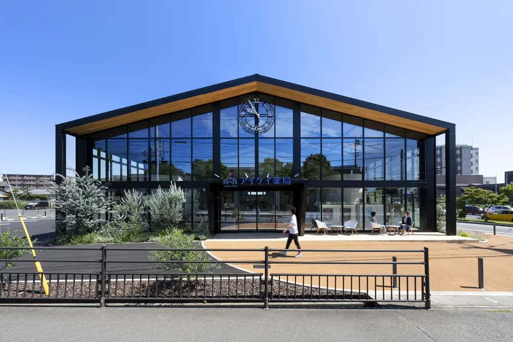 The façade is surrounded by glass windows on three sides, reflecting the sky during the day and allowing bright sunlight to pour into the pharmacy. There is also outdoor seating so you can relax as if you were in a cafe.