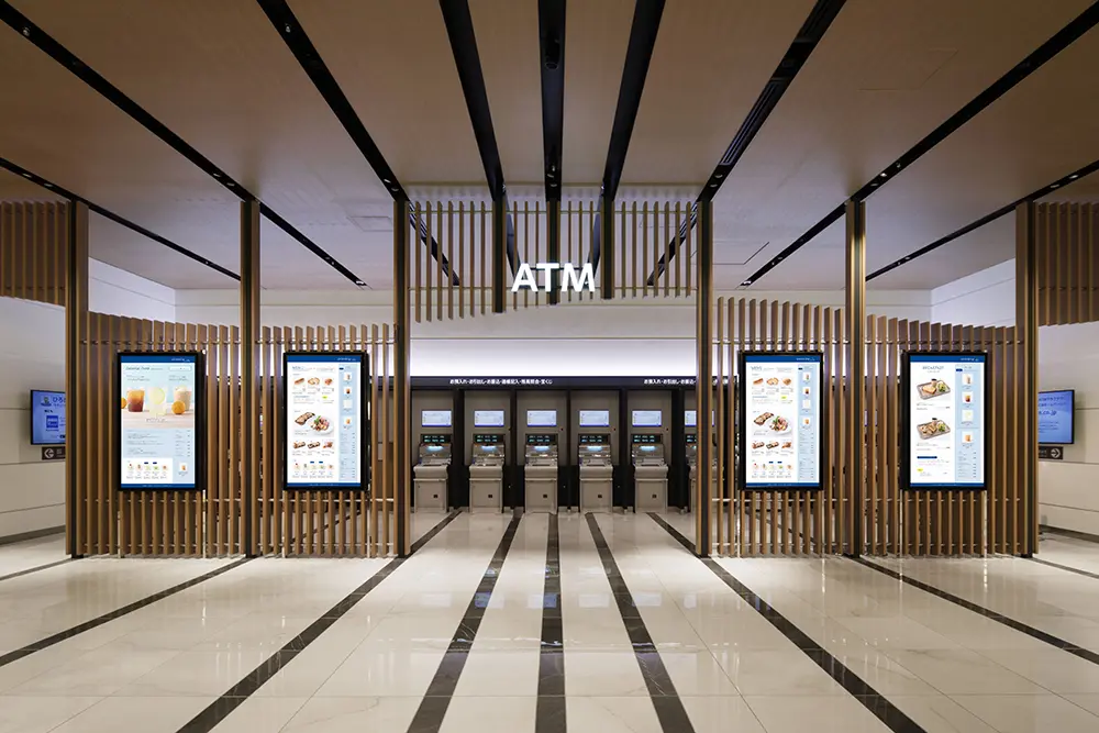 An ATM area that is easy to use while still being connected to the public space. Digital signage displays promotional information for the bank and local information.