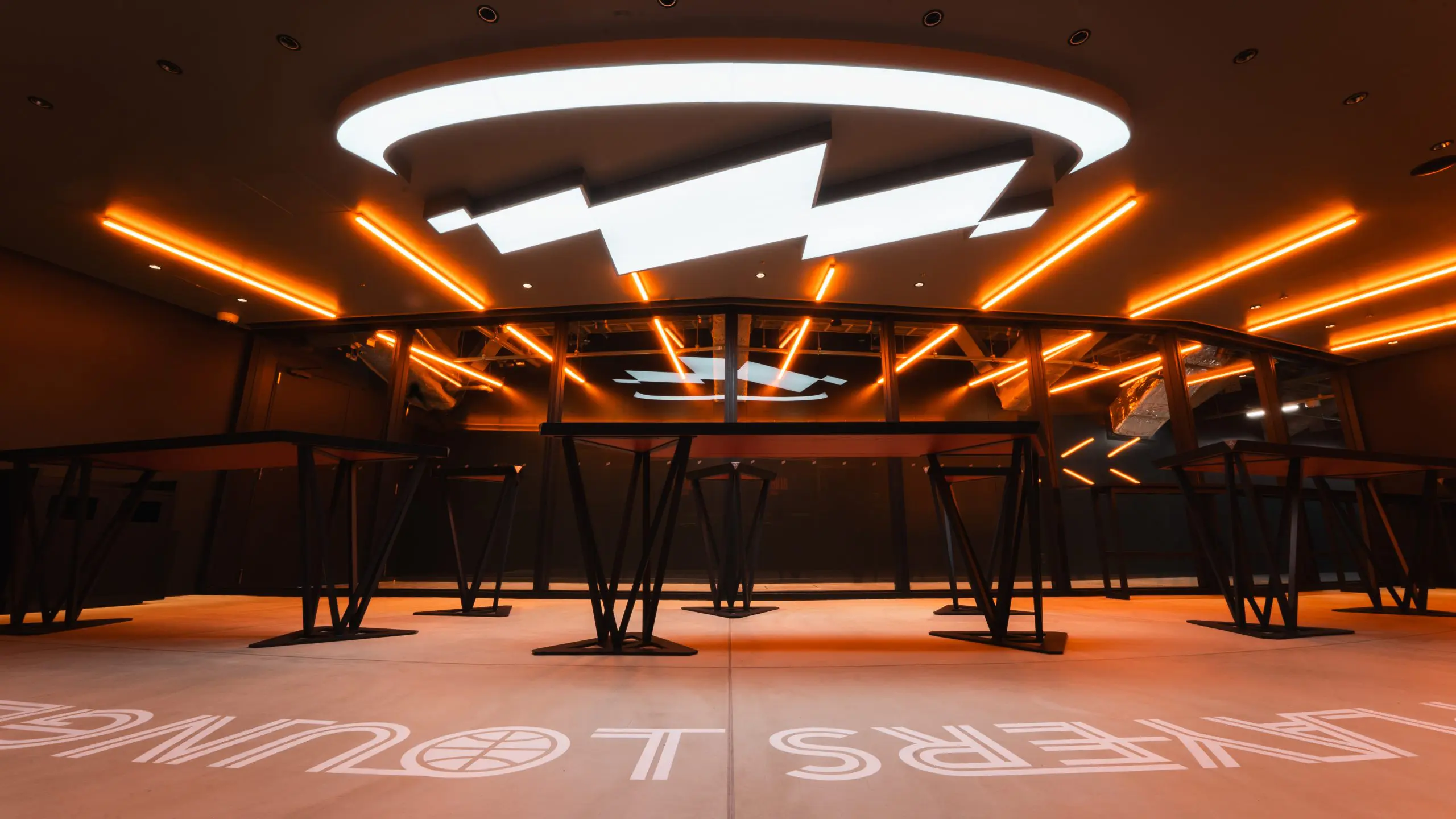 Line lighting extends from the path of players across the glass, and the arena logo is displayed prominently on the ceiling.