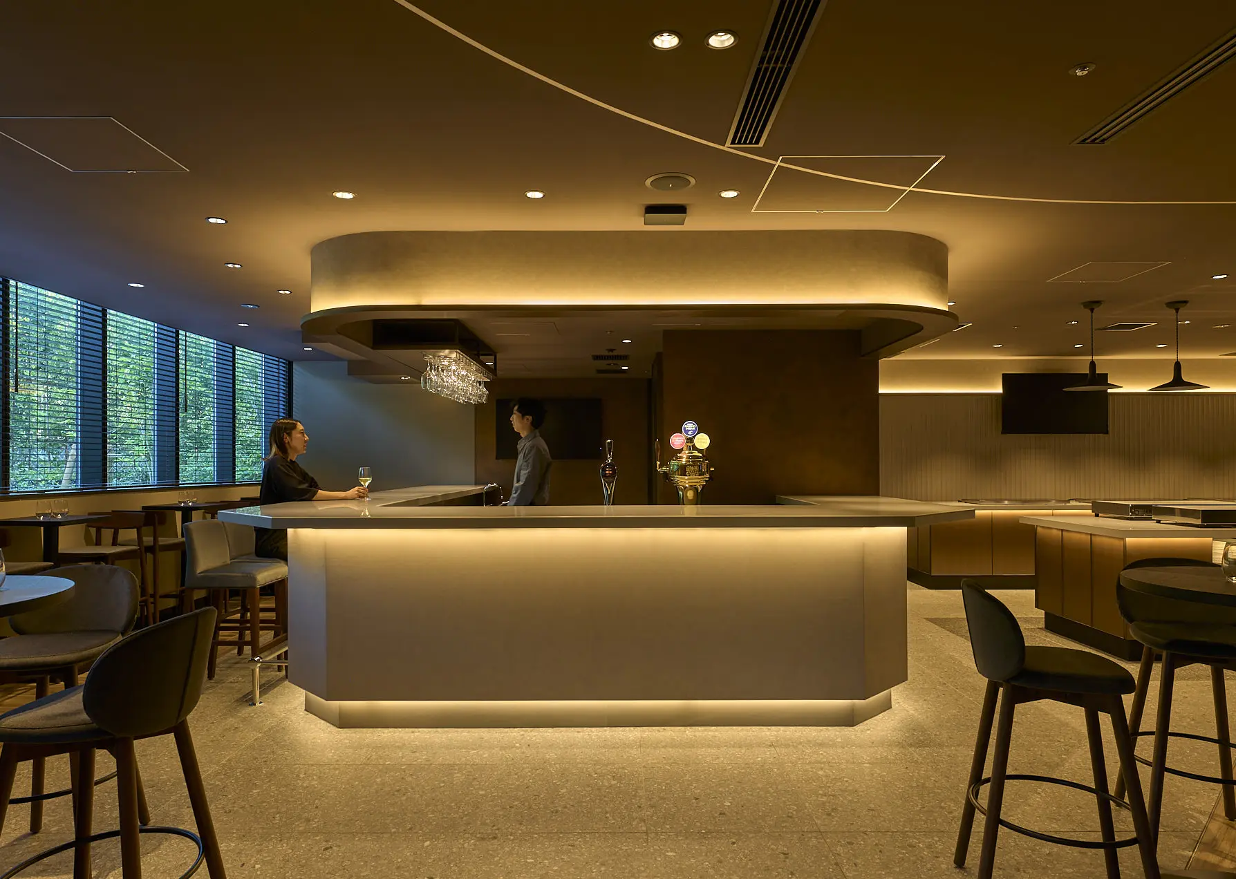 The bar area in the back. The overall color tone and texture are coordinated to create a sense of unity.