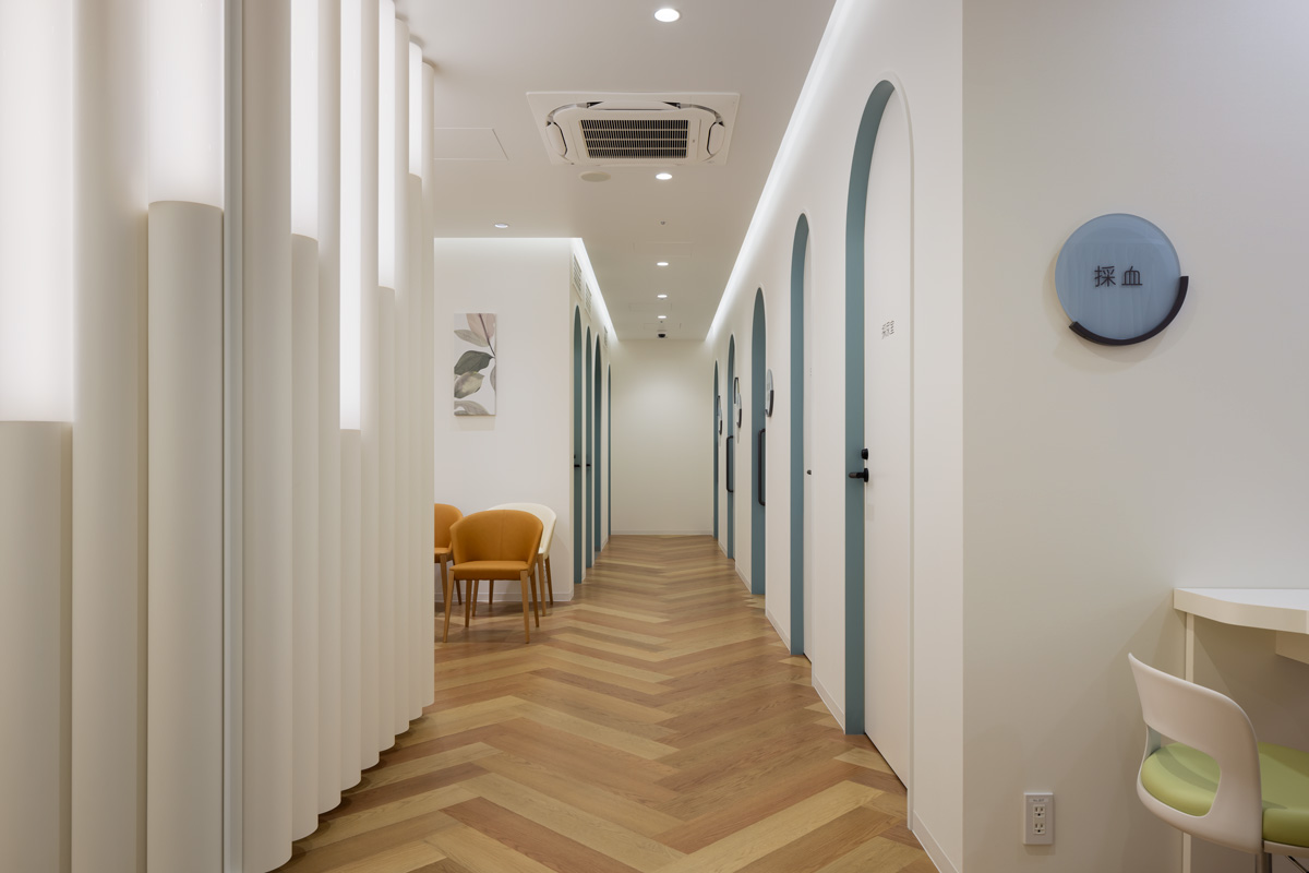 クリニック内部の廊下は木目床のパターンと扉小口のカラーでリズム感を持たせた