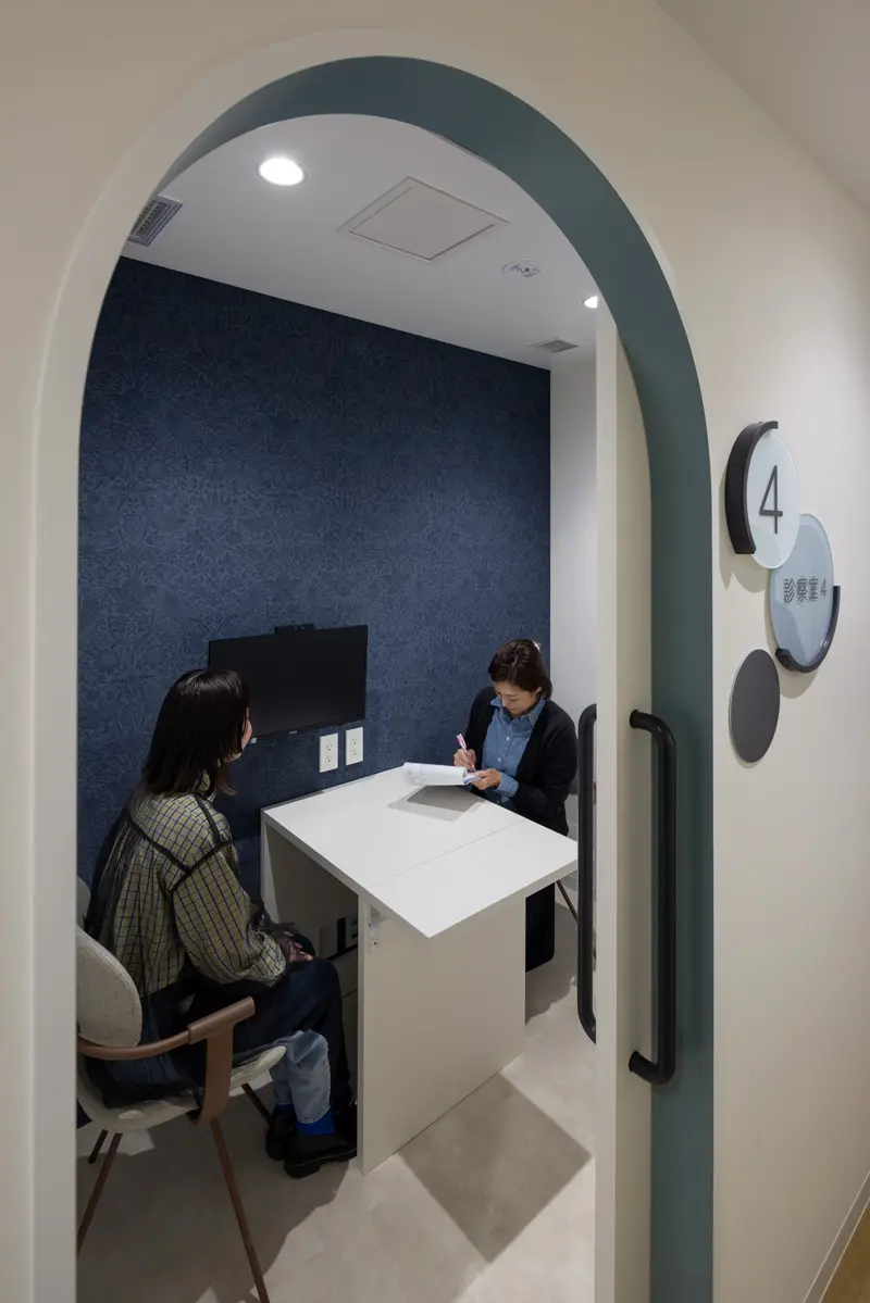 There is also an examination room where online consultations can be conducted. The interior is designed to be a relaxing space with a calm color scheme.
