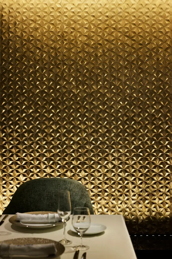 Champagne gold steel mosaic tiles with geometric patterns create a luxurious atmosphere.