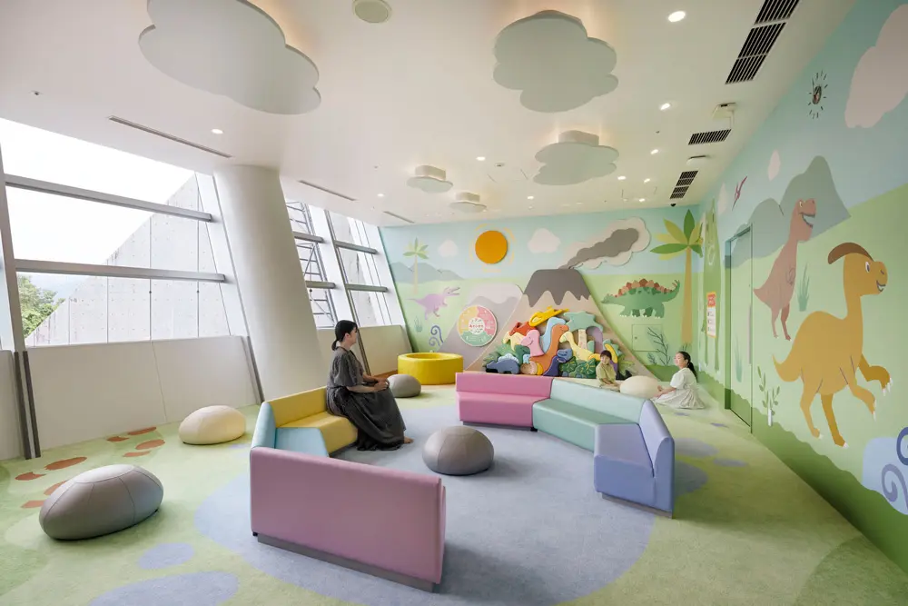 A kids' space where parents and children can relax. Dinosaur puzzles are set up on the walls, creating a dinosaur-themed play space.