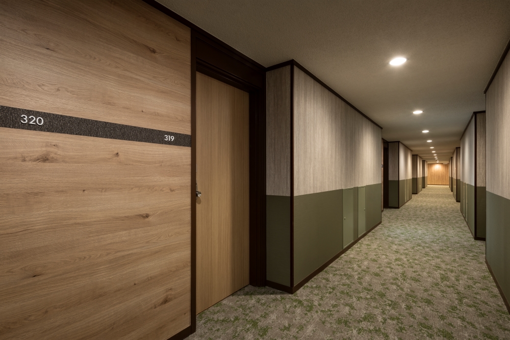 The corridors also incorporate the texture of wood and forest green, creating a sense of unity with the guest rooms.