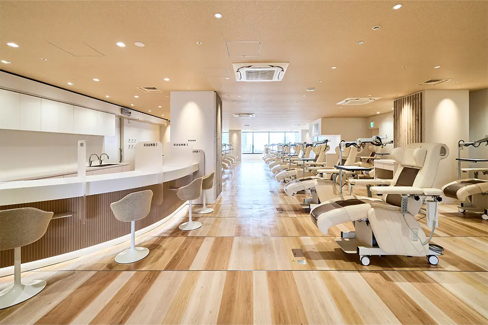 A blood collection room with a tranquil atmosphere, featuring a woven fabric ceiling and wooden flooring.