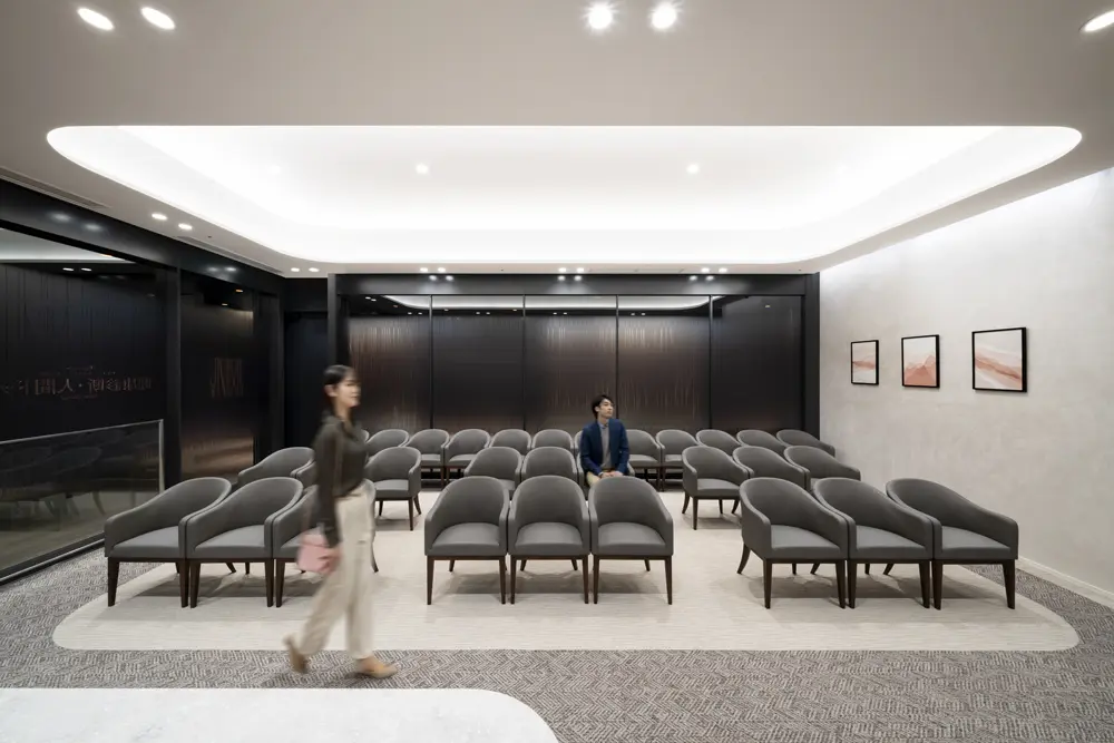 The waiting area in front of the reception desk is bathed in soft light from indirect lighting on the ceiling.