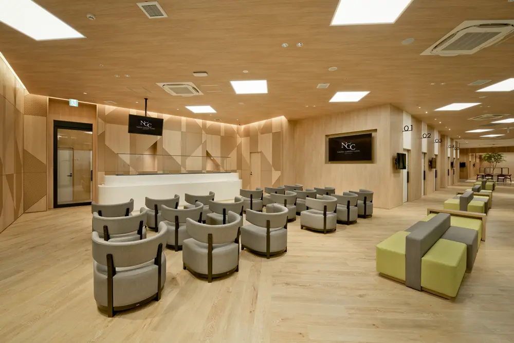 Outpatient reception space: Wooden walls and soft lighting that blend in with the lush green surroundings of the facility create a sense of openness.
