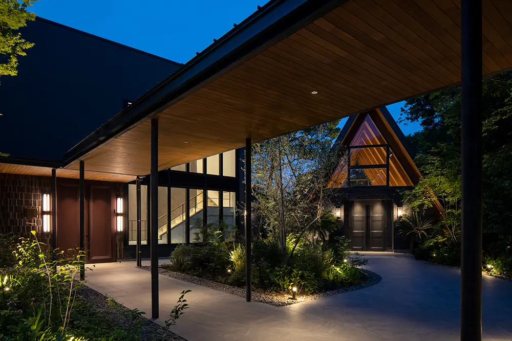 The newly constructed guest house and music hall. The exterior is painted gray to match the black plaster of the house, and the lighting for the exterior is less bright than that of the house, creating a sense of unity.