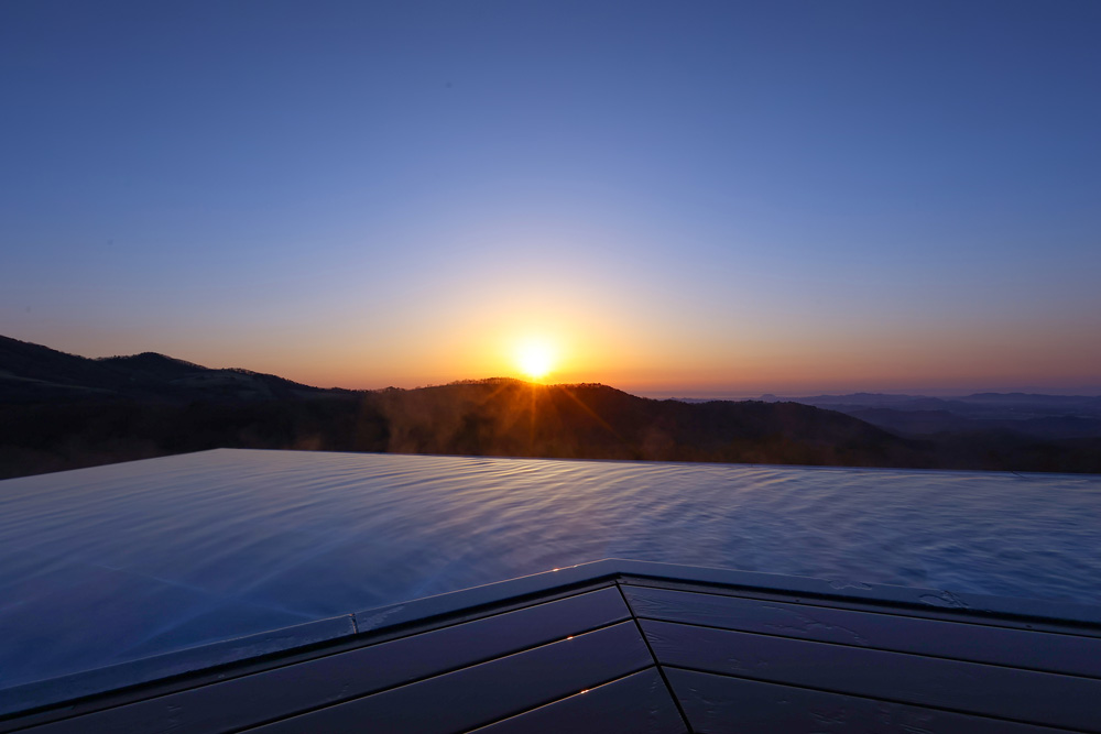 The open-air rooftop bath offers a beautiful view of the morning glow and a sense of the majestic nature. The facility was designed with the idea in mind that the greatest value of the facility is nature. (Photo: Satoshi Imai, Image provided by Ooedo Onsen Monogatari Hotels & Resorts Co., Ltd.)