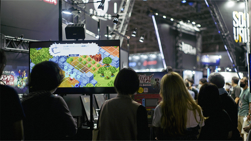 By setting up monitors facing the waiting line and showing Video of the game being played on the spot, the company was able to attract visitors' interest and increase the number of people who tried out the game.