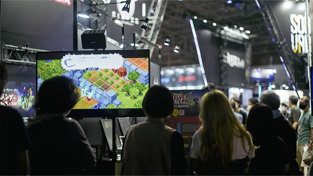 By setting up monitors facing the waiting line and showing Video of the game being played on the spot, the company was able to attract visitors' interest and increase the number of people who tried out the game.