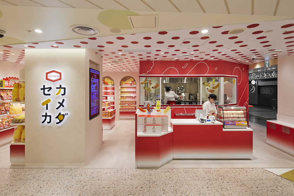 カメダセイカ：米菓のイメージチェンジがコンセプト。 ブランドロゴの赤を基調とした店内にお菓子のグラフィックをちりばめたポップな店舗デザイン