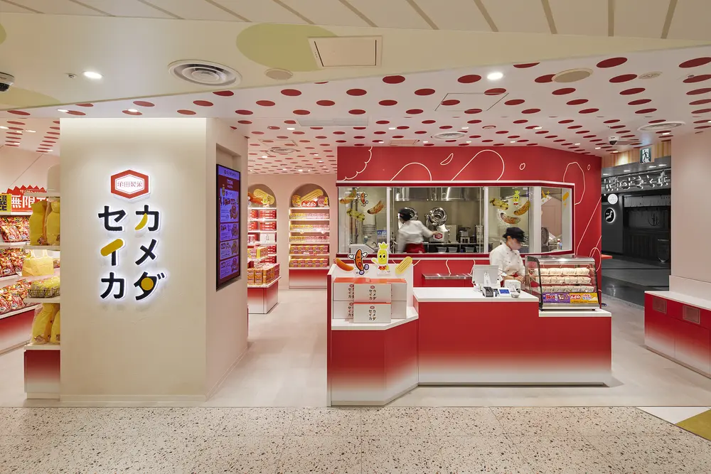 カメダセイカ：米菓のイメージチェンジがコンセプト。 ブランドロゴの赤を基調とした店内にお菓子のグラフィックをちりばめたポップな店舗デザイン